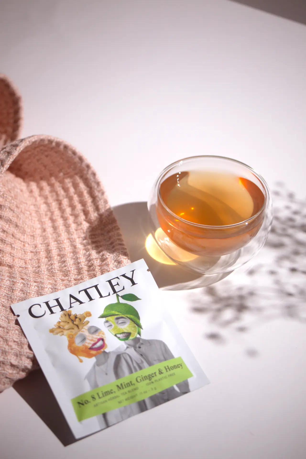 Chatley No. 8 sachet beside a glass of brewed herbal tea on a folded waffle towel